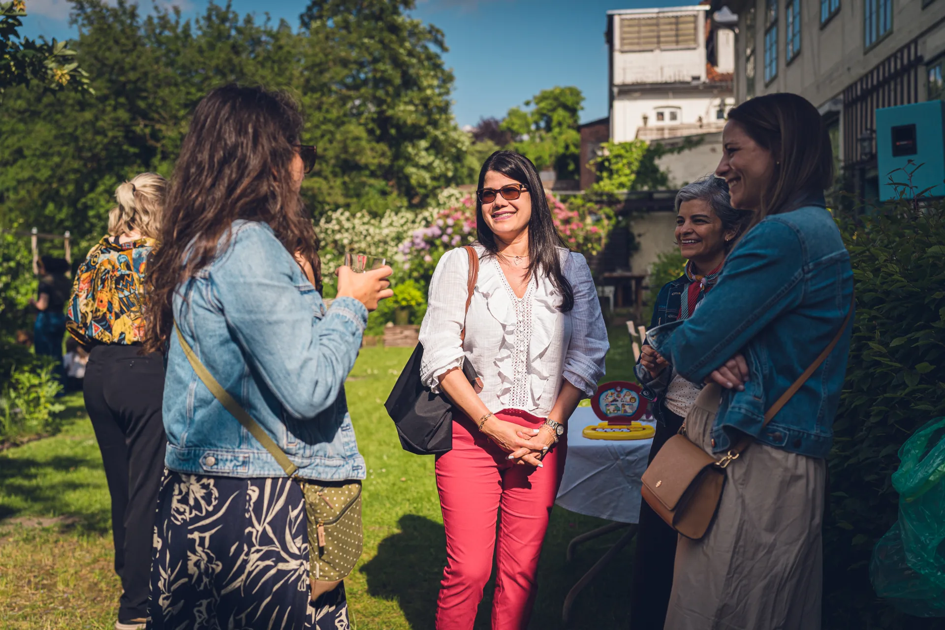 Frauen stehen im sonnigen Garten zusammen und unterhalten sich.