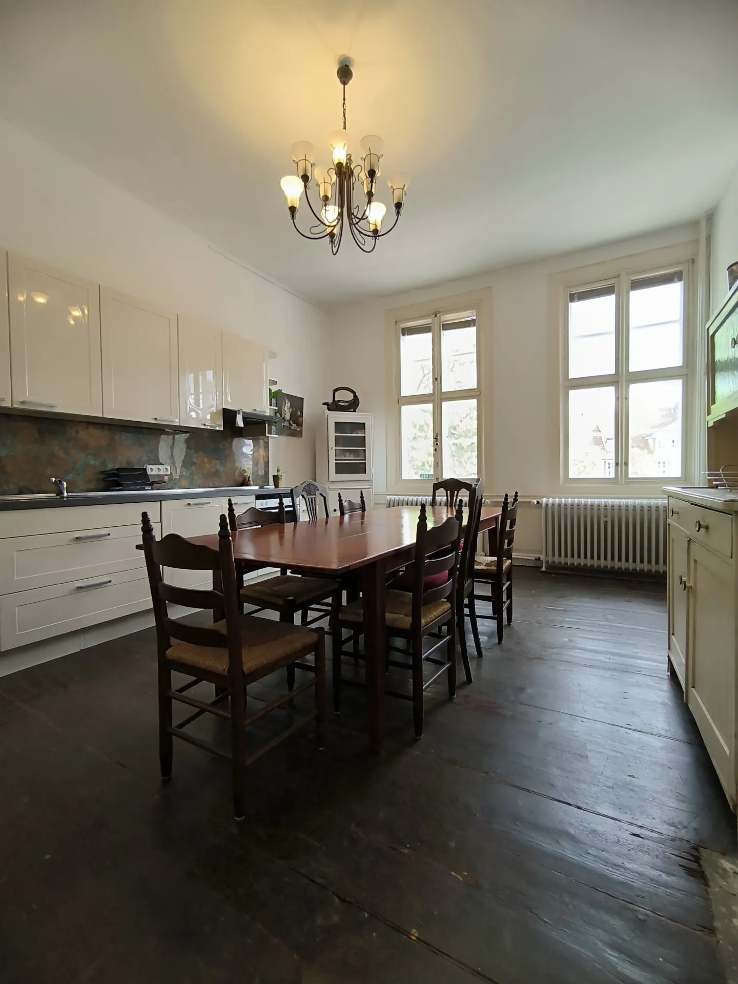Die große Küche mit langem Tisch und offenen Regalen.