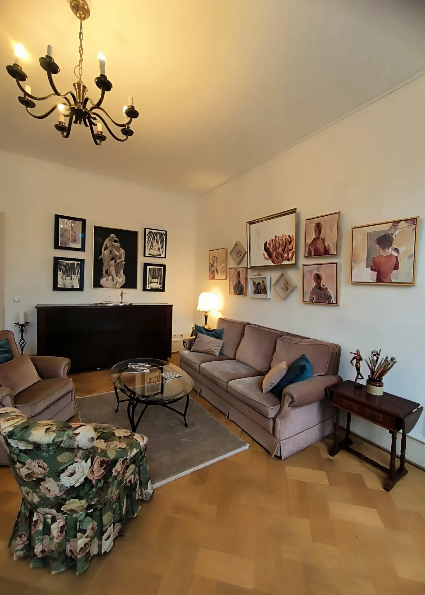 Wohnzimmer in der Trift 32 mit Sofa, Sesseln und einer Wand voller Bilder.