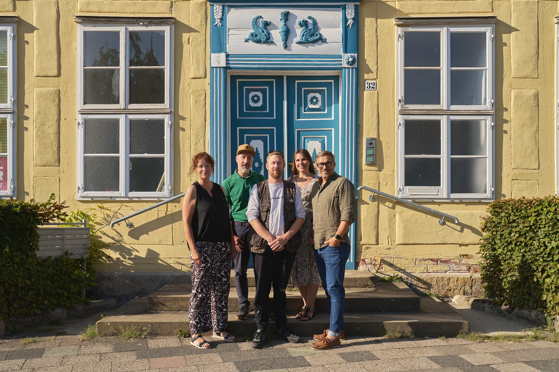 Die fünf Mitglieder der Jury stehen vor der gelben Fassade und der blauen Haustür der Trift 32.